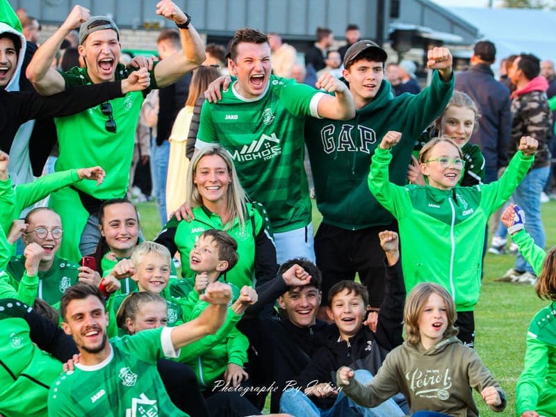 Les jeunes du RFC Sart, poings levés, fêtent la montée en P1 sur le terrain aux côtés des joueurs et des entraîneurs